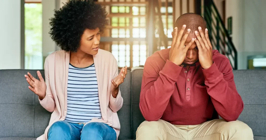 Woman appears to be Gaslighting (blaming) Man In argument. Both seated on couch.